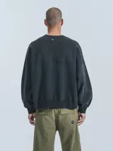 Buzo negro de cuello redondo, corte oversize y largo crop. Confeccionado en frisa gamuzada de algodón con recortes de microfibra y bolsillo delantero con cierre a presión.