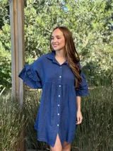 Vestido camisero azul de lino italiano, con cuello camisero, botones frontales, mangas 3/4 con doble volado y bolsillos laterales.