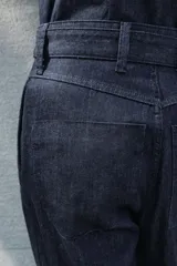 Pantalón de jean azul oscuro, corte wide leg, tiro alto, con cinturón de la misma tela y hebilla metálica.