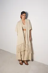 Ruana color beige de tejido de punto con flecos en el ruedo.