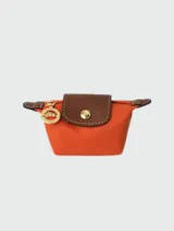 Monedero Longchamp Le Pliage Original color naranja con detalles en cuero marrón y herrajes dorados.