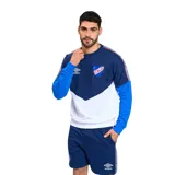 Buzo de frisa azul marino, blanco y celeste con cuello redondo, puños y cintura acanalados. Presenta el logo de Umbro bordado en blanco en el pecho izquierdo, el escudo del Club Nacional de Football bordado en el pecho derecho y una cinta con diseño geométrico en los hombros.