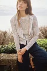 Cárdigan de punto con estampado floral en tonos rosa, gris y blanco. Tiene cuello redondo, manga larga, rib en los puños y el bajo, y cierre frontal con botones.
