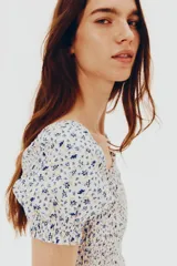 Vestido corto de popelina de algodón con estampado floral azul. Presenta escote cuadrado con elástico, mangas cortas abullonadas con fruncido elástico, cuerpo ajustado fruncido y falda con vuelo.