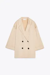 Blazer color beige de cuello solapa y manga tres cuartos. Tejido con efecto arrugado y cierre frontal cruzado con botones negros.