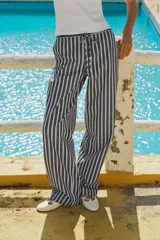 Pantalón de tiro medio con cintura elástica ajustable con cordones, bolsillos delanteros y traseros de parche. Pierna ancha con estampado de rayas verticales azules y blancas.