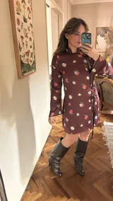 Vestido corto color borgoña con estampado de rosas y limones, mangas largas, cuello mao y cierre lateral con lazos negros.