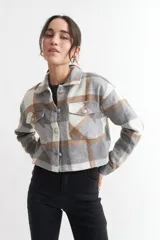 Chaqueta corta a cuadros grises, blancos y marrones, con cuello clásico, cierre frontal con botones y bolsillos con solapa en el pecho.