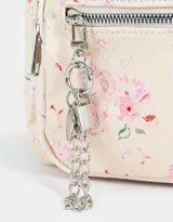 Mochila urbana negra de cuerina con bolsillo frontal con cierre y charm colgante de cadena con dije de corazón y candado. Tiene correas regulables, manija superior, cierre superior, doble bolsillo frontal (uno con charm metálico) y bolsillos laterales.