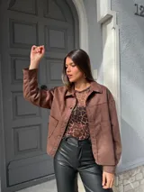 Chaqueta marrón de gamuza con cuello camisero, cierre frontal con botones y bolsillos de parche en el pecho.