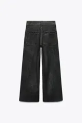 Pantalón de jean de tiro alto color negro con pierna ancha, bolsillos delanteros y traseros, y cierre frontal con cremallera y botón metálico.