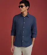 Camisa marrón claro de lino, de corte clásico, con cuello inglés, manga larga y cierre frontal con botones blancos.