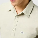 Camisa de manga larga color verde claro, con cuello clásico, cierre con botones y bolsillo en el pecho.