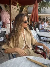 Blusa color beige de lino con puntilla de algodón en el escote y mangas abullonadas con elástico en los puños.