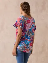 Blusa estampada con motivos florales en tonos rosa, azul y naranja. Tiene cuello en V y mangas cortas con volados.