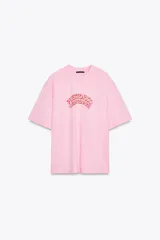 Camiseta rosa de algodón con efecto lavado, corte regular, cuello redondo y mangas cortas. Estampado frontal con la frase "Puerto Rico Vuela Conmigo".