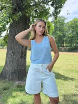 Top de tejido de punto color celeste, sin mangas y con cuello redondo. Presenta un patrón calado de rayas horizontales con pequeños orificios.