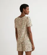 Blusa de crepé color beige con estampado de lunares de colores, cuello redondo con ribete negro, manga corta abullonada, bolsillo de parche en el pecho y bajo mullet con aberturas laterales.