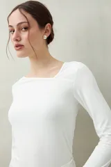 Top blanco de manga larga con escote asimétrico.