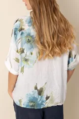 Camisa de lino blanca con estampado de flores azules y verdes, de corte holgado y manga corta.