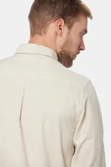 Camisa de lino color beige, de manga larga, con cuello clásico y bolsillo en el pecho.