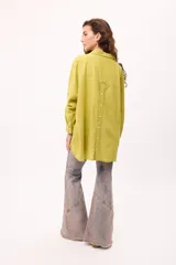 Camisa oversize a rayas verticales color amarillo y blanco, con cuello camisero, manga larga y cierre frontal con botones.