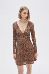 Vestido corto color beige con estampado animal print, escote en V, mangas largas y falda evasé con volados. Ajuste con lazo en la cintura.