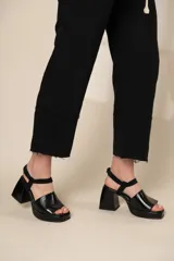 Sandalias negras de cuero con plataforma y taco cuadrado. Tiras anchas sobre el empeine y pulsera al tobillo con hebilla.
