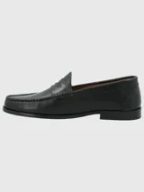 Zapato mocasín de cuero color marrón, con detalle de antifaz y suela de cuero y goma.