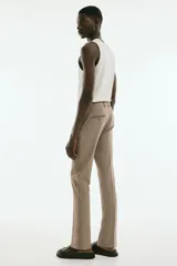 Pantalón de vestir color beige, corte slim fit, con cierre de botón, bolsillos laterales y bolsillos traseros ribeteados con botón.