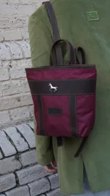 Mochila pequeña color borgoña con detalles en cuero marrón, asa de mano y correas ajustables.