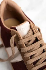 Zapatillas deportivas marrones con detalles en color borgoña y blanco, con cordones y suela de goma.
