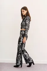 Pantalón de terciopelo negro con estampado floral plateado, corte acampanado y tiro alto.