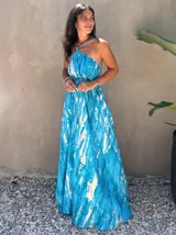 Vestido largo de tela fluida, color azul vibrante con estampado tie-dye en tonos beige/crudo. Diseño halter con tirantes finos ajustables y cintura marcada con lazo.