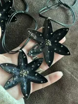 Gargantilla negra con colgante en forma de flor negra con detalles de mostacillas plateadas.
