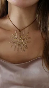 Collar con dije grande de bronce con forma de sol y cordón de cuero marrón ajustable.