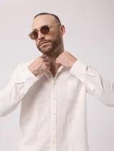 Camisa de manga larga azul, de lino y poliéster, con cuello abotonado y bolsillo en el pecho.