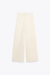 Pantalón de vestir color crudo, de tiro alto, corte recto y textura arrugada. Cuenta con cintura elástica ajustable con cordones.