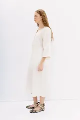 Vestido midi tipo túnica color blanco, de lino y algodón. Tiene calce recto, escote redondo con botones y bordados en hilo en el frente, sisas y ruedo.