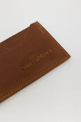 Tarjetero de cuero marrón con costuras en los bordes y logo de la marca SierraMora grabado en el frente. Tiene ranuras para tarjetas en ambos lados.