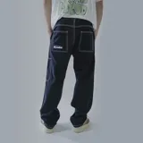 Pantalón negro de gabardina, corte recto, con costuras blancas contrastantes y bolsillos laterales.