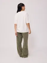 Remera color crudo de corte oversized con estampado de palmeras, flores y texto 'California' y 'Rusty Tribe'.