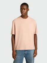 Remera de algodón color rosa pálido, con cuello redondo y manga corta. Presenta un dobladillo deshilachado en el cuello y en los bordes de las mangas.