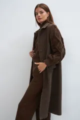 Tapado largo y recto color marrón con mangas tejidas con diseño de trenzas. Tiene cuello solapa, cierre frontal con botones ocultos y bolsillos con solapa. Con forro.