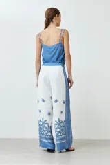 Pantalón blanco con estampado floral y guarda geométrica en tonos de azul.