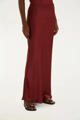 Falda larga color borgoña de satén con ribete de encaje en el bajo, talle medio y cierre lateral.