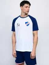 Remera blanca con mangas raglán azul marino, cuello redondo y logo del Club Nacional de Football estampado en el pecho.