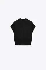 Jersey negro de punto con cuello solapa, manga corta y detalle de lentejuelas plateadas y negras.