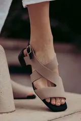 Sandalias de cuero color beige con tiras cruzadas y hebilla lateral. Taco cuadrado color marrón oscuro.