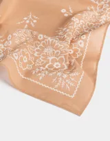 Pañuelo cuadrado de algodón color beige con estampado floral blanco.